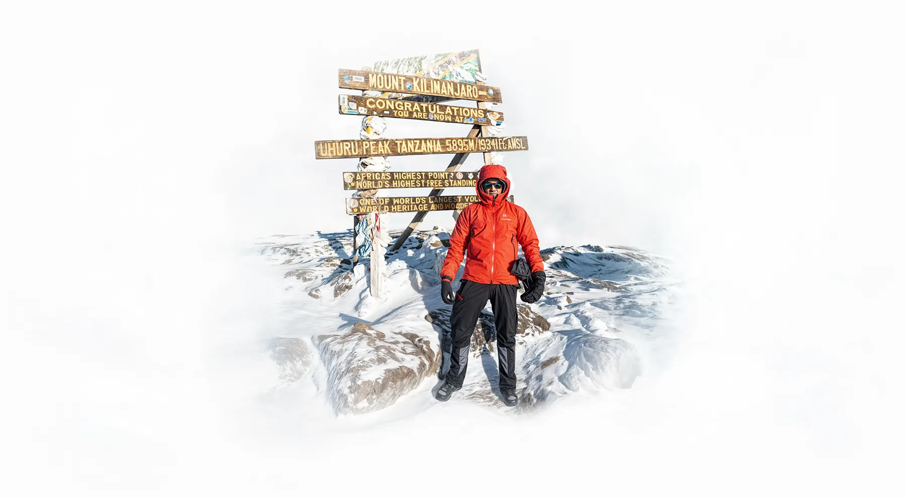Klimmer bij het Uhuru Peak-topbord op de Kilimanjaro Klimmer bij het Uhuru Peak-topbord op de Kilimanjaro